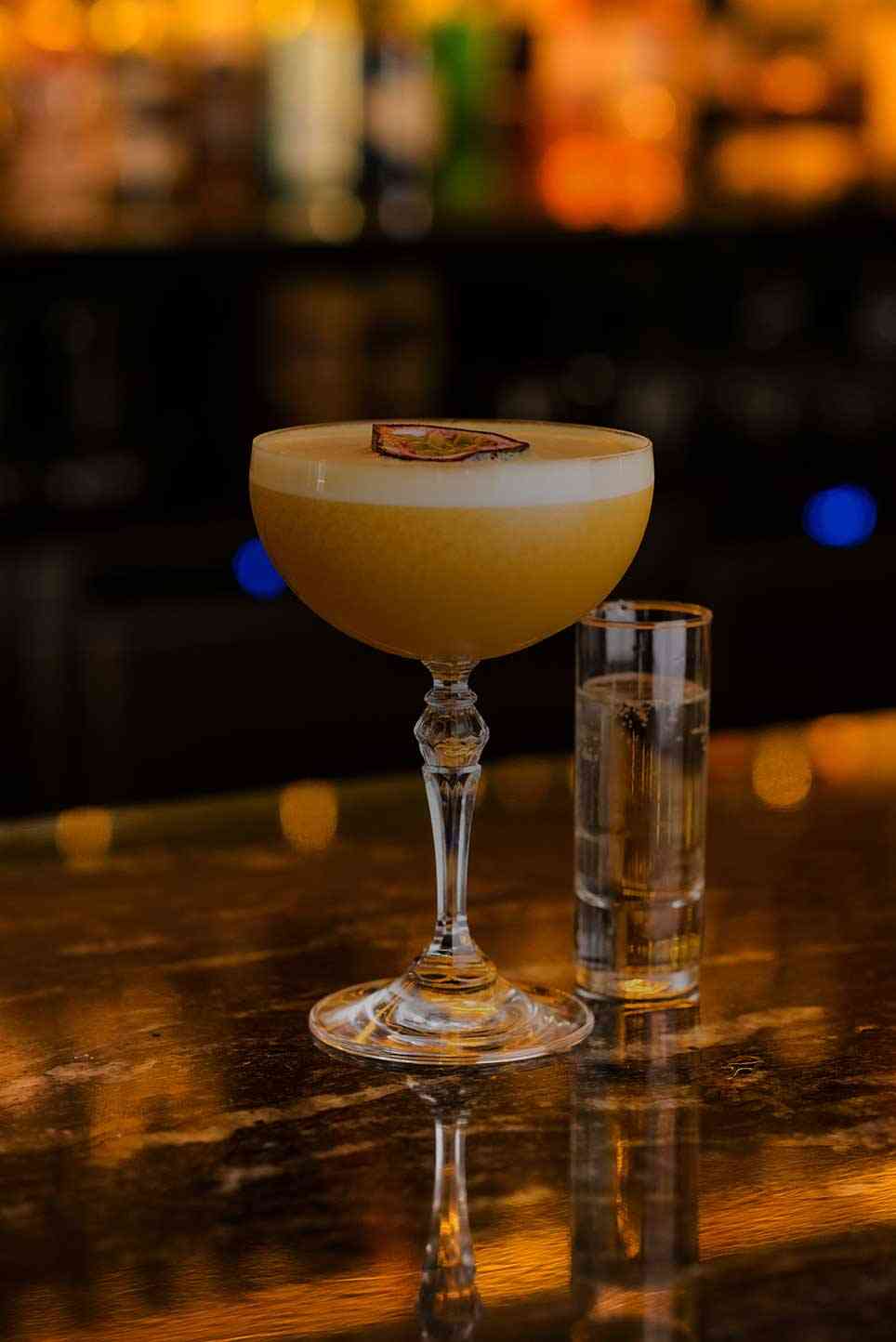 A sour-style cocktail on the back-lit Siamais bar